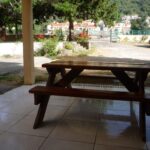 un grand banc en bois dans une terrasse avec vu sur un grand jardin